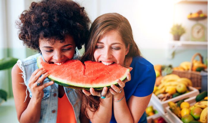 Two women eating the same watermelon