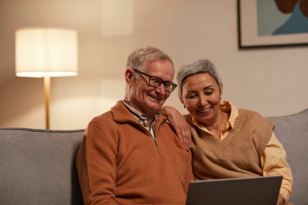 husband and wife sitting on a couch looking at a laptop