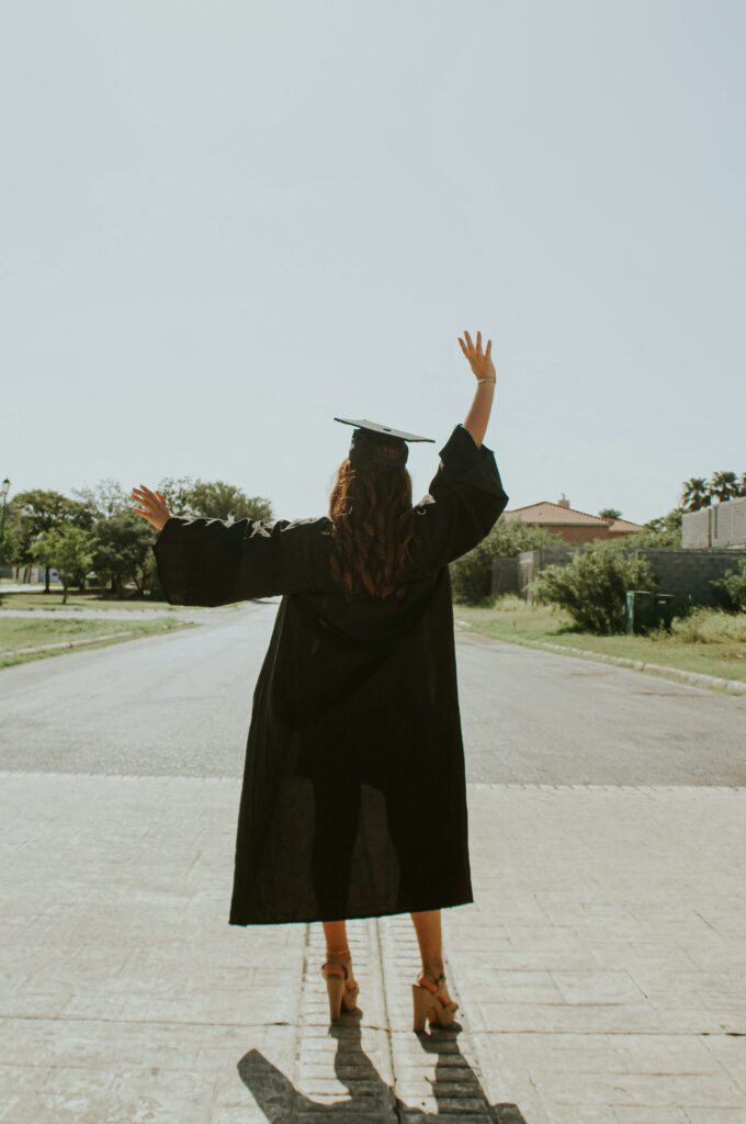 Anonymous woman in graduate outfit on street