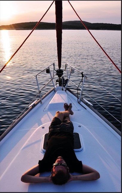 a man lying down on a yatch looking at the sky