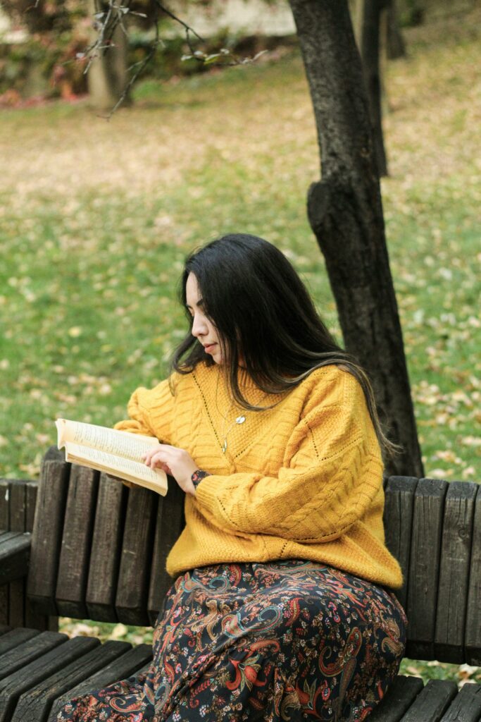 a lady reading book on a feild