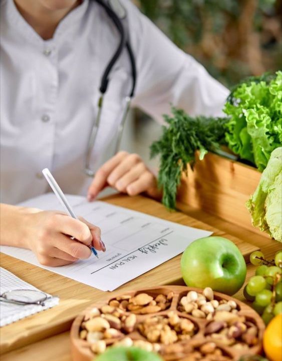 someone writing with apple in front of her and stethoscope on her neck