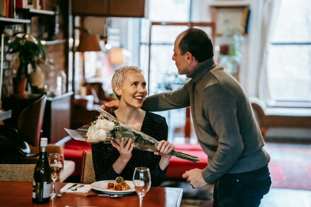 Couple having date in restaurant with flowers bouquet and food