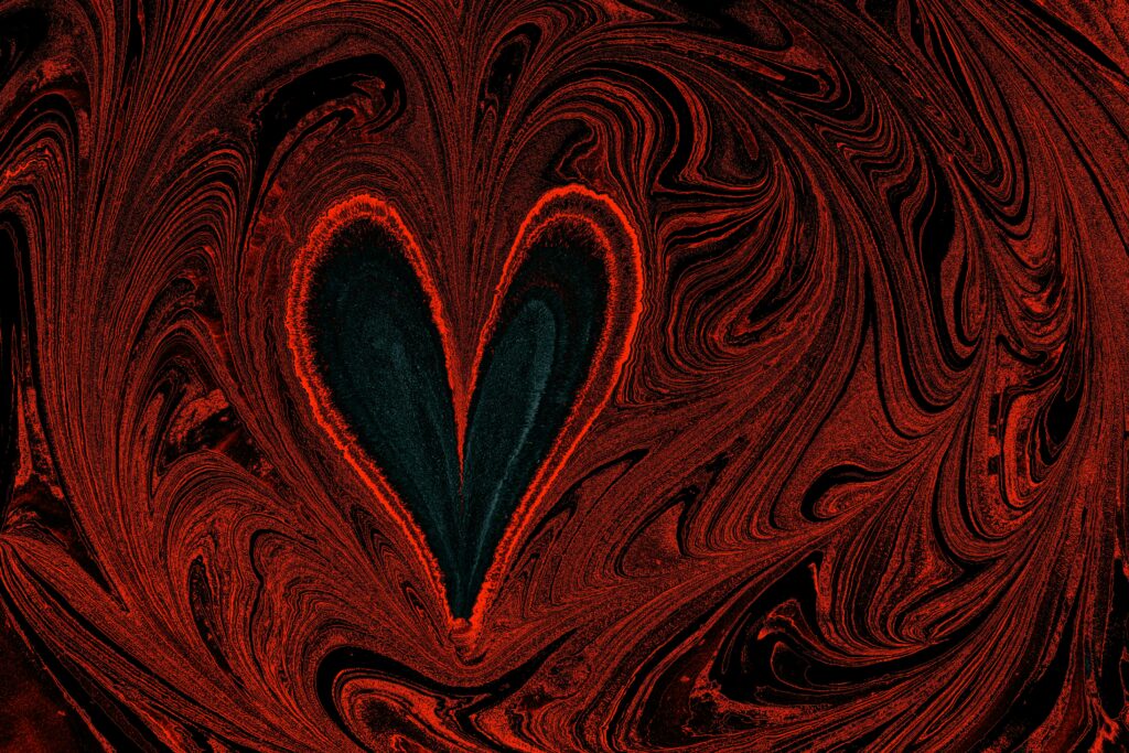 A red heart with black swirls on a black background