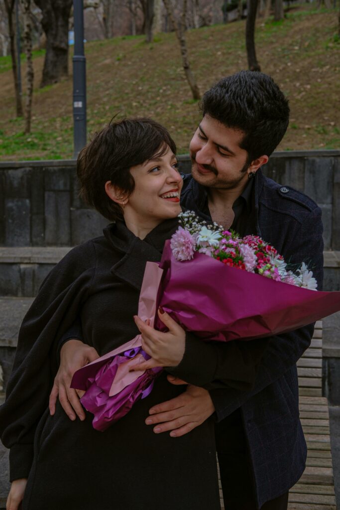 A man and woman holding flowers and hugging